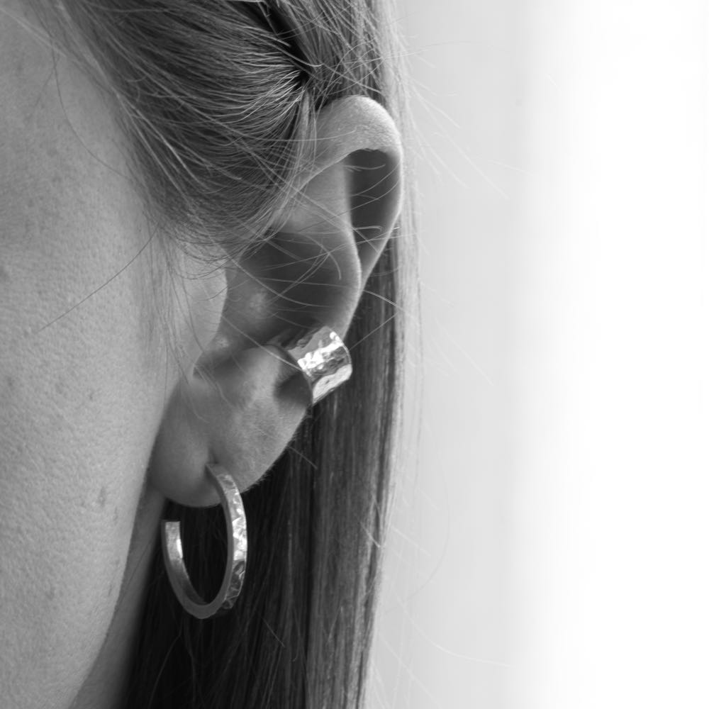 Bred ear cuff i silver, buren på en dams öra i en stilren vardagslook