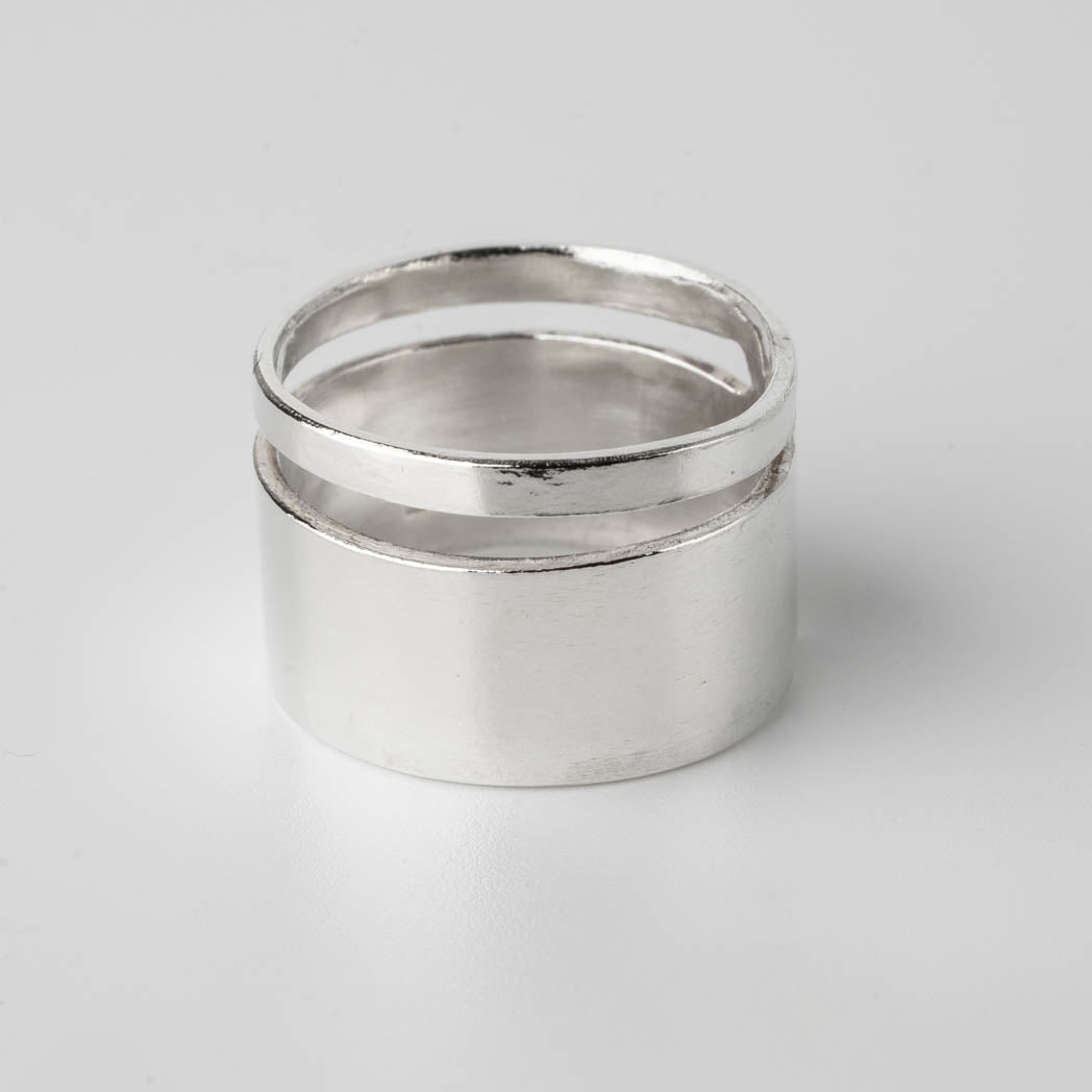 Bred silverring i Àkta silver med en utskuren rand som nÀstan gÄr runt hela ringen, handgjord och unik, fotograferad mot vit bakgrund.