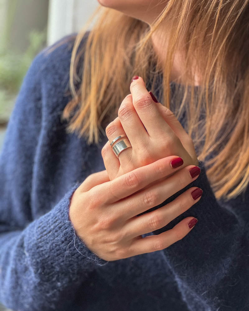 VÄr breda silverring Lysande Rand pÄ en kvinnas hand.