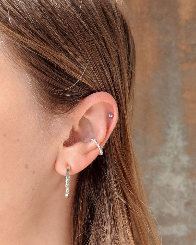 Kvinna som bÀr en bubblig ear cuff i 925 sterlingsilver.
