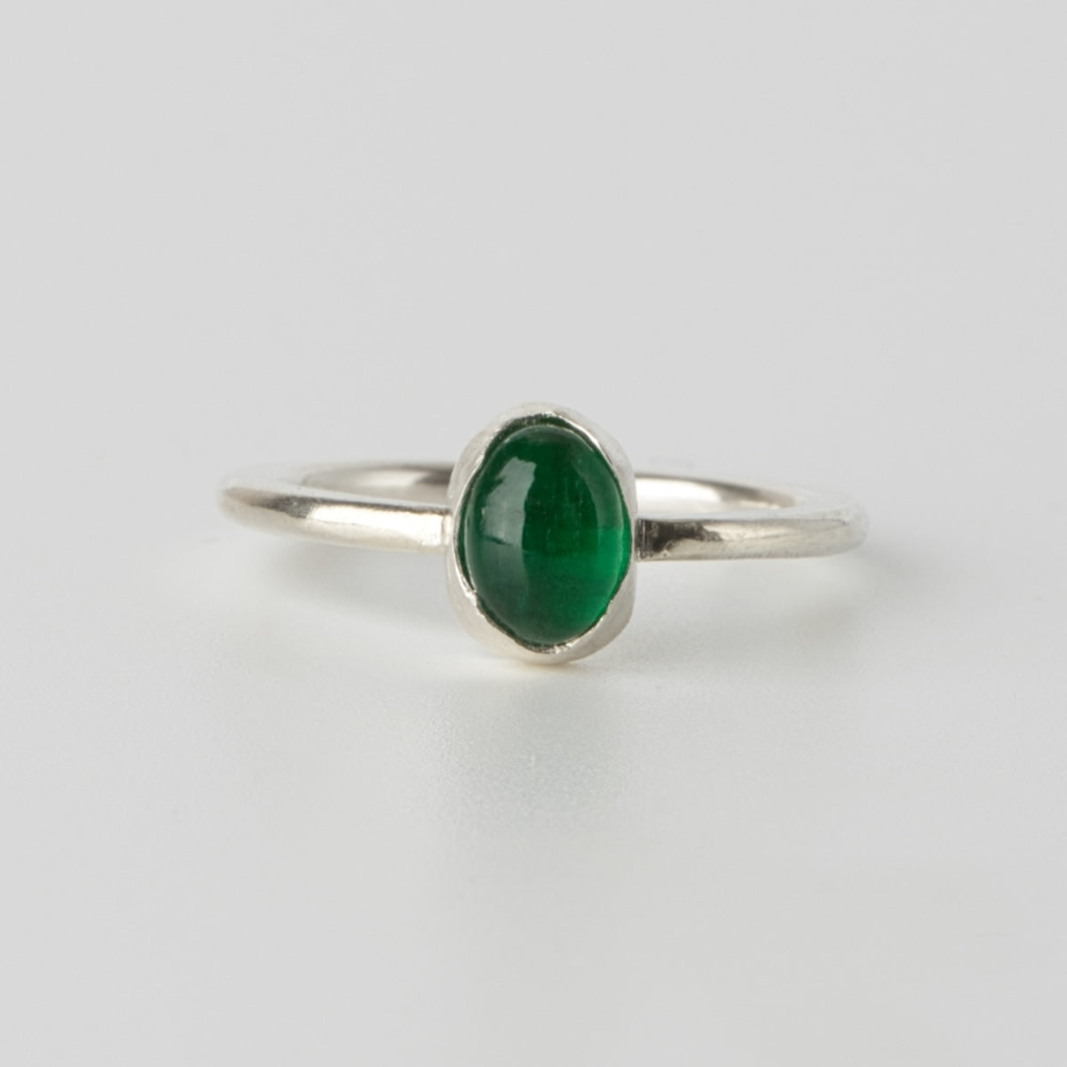 Handgjord silverring med naturlig smaragd i cabochonslipning, fotograferad framifrån.