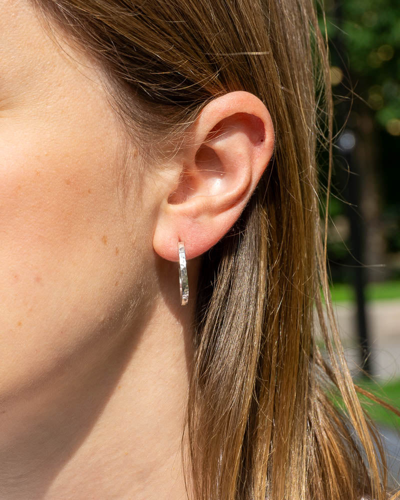 Profilvy av en kvinna som bÀr vÄrt silverhoops örhÀnge med hamrad yta och kantiga kanter i Àkta sterlingsilver.