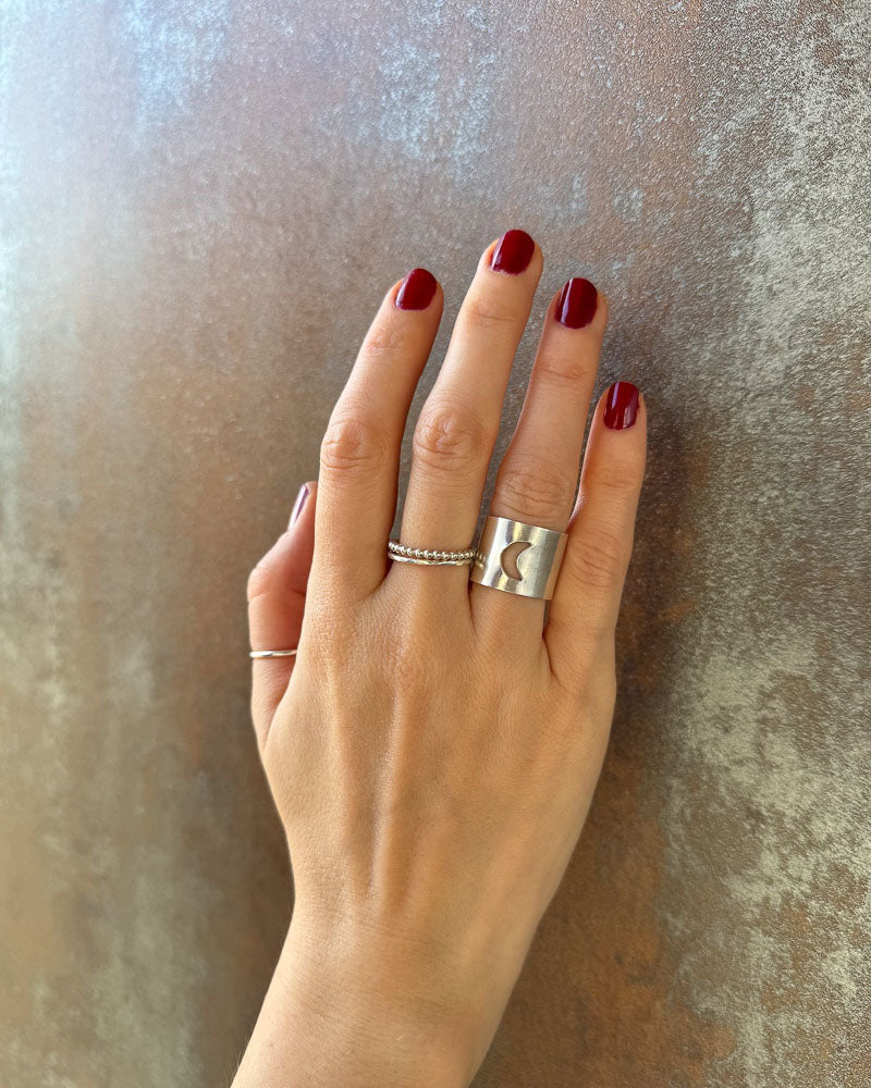 Hand bÀr en bred silverring med en utsÄgad mÄnskÀra, design Nude Stockholm.