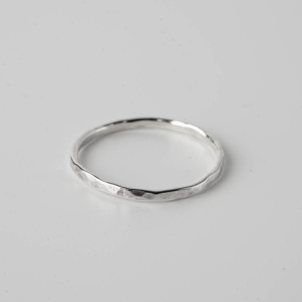 Hamrad tunn ring – handgjord silverring i 925 sterlingsilver, 1,25 mm tjock, med en hamrad design, fotograferad mot vit bakgrund.