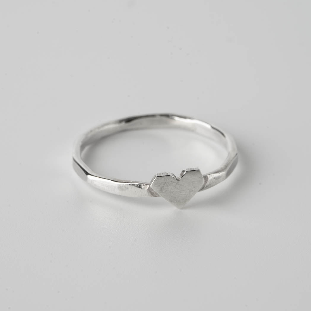 Hjärta – handgjord tunn silverring i 925 sterlingsilver, 1,25 mm tjock, med ett asymmetriskt hjärta, fotograferad mot vit bakgrund.