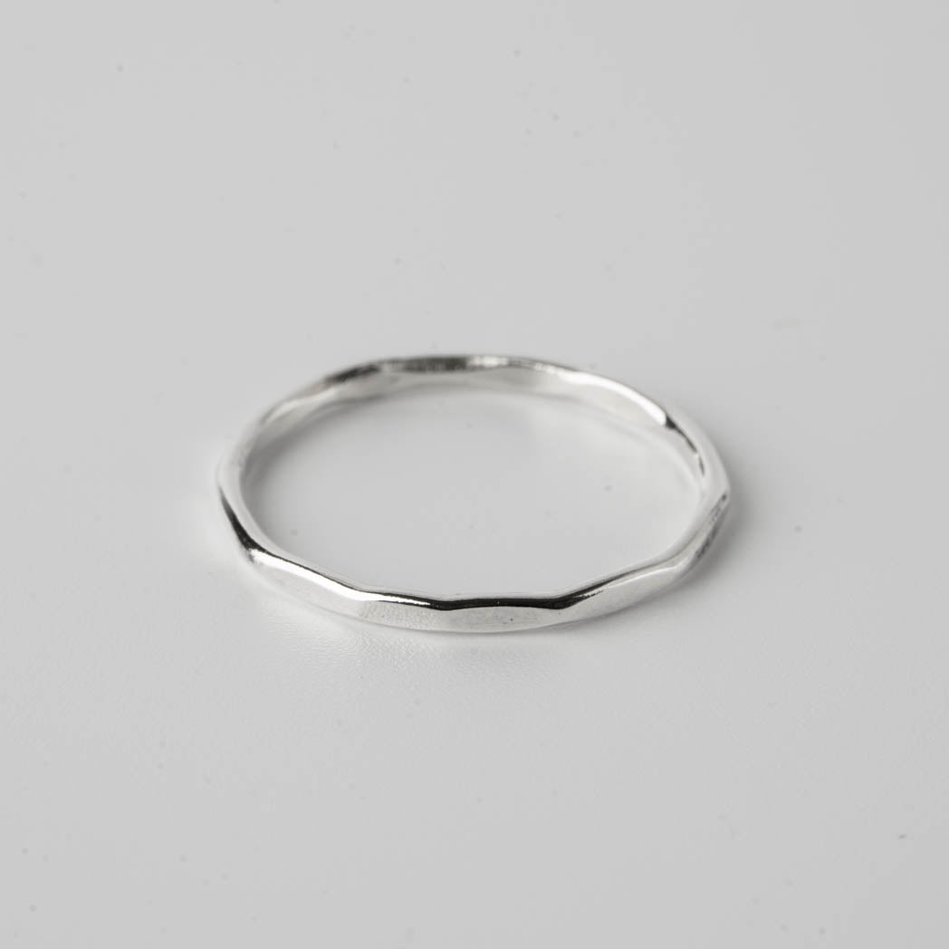 Kantig ring â handgjord tunn silverring i 925 sterlingsilver, 1,25 mm tjock, med en strukturerad kantig design, fotograferad mot vit bakgrund.
