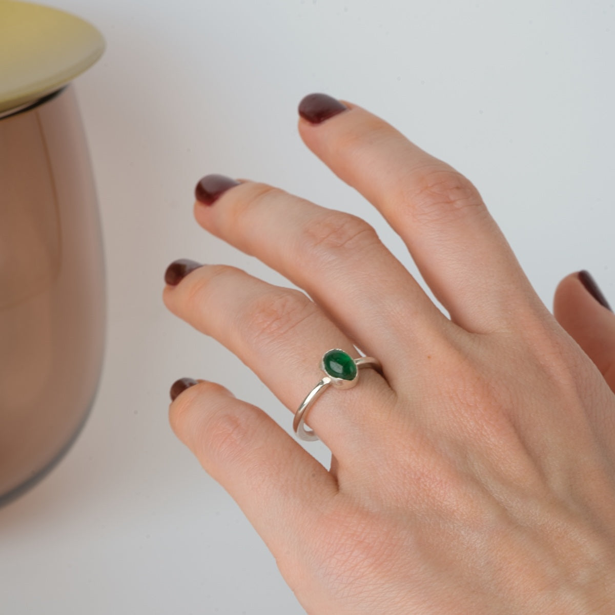 Närbild ovanifrån på en hand med handgjord silverring med cabochonslipad smaragd.