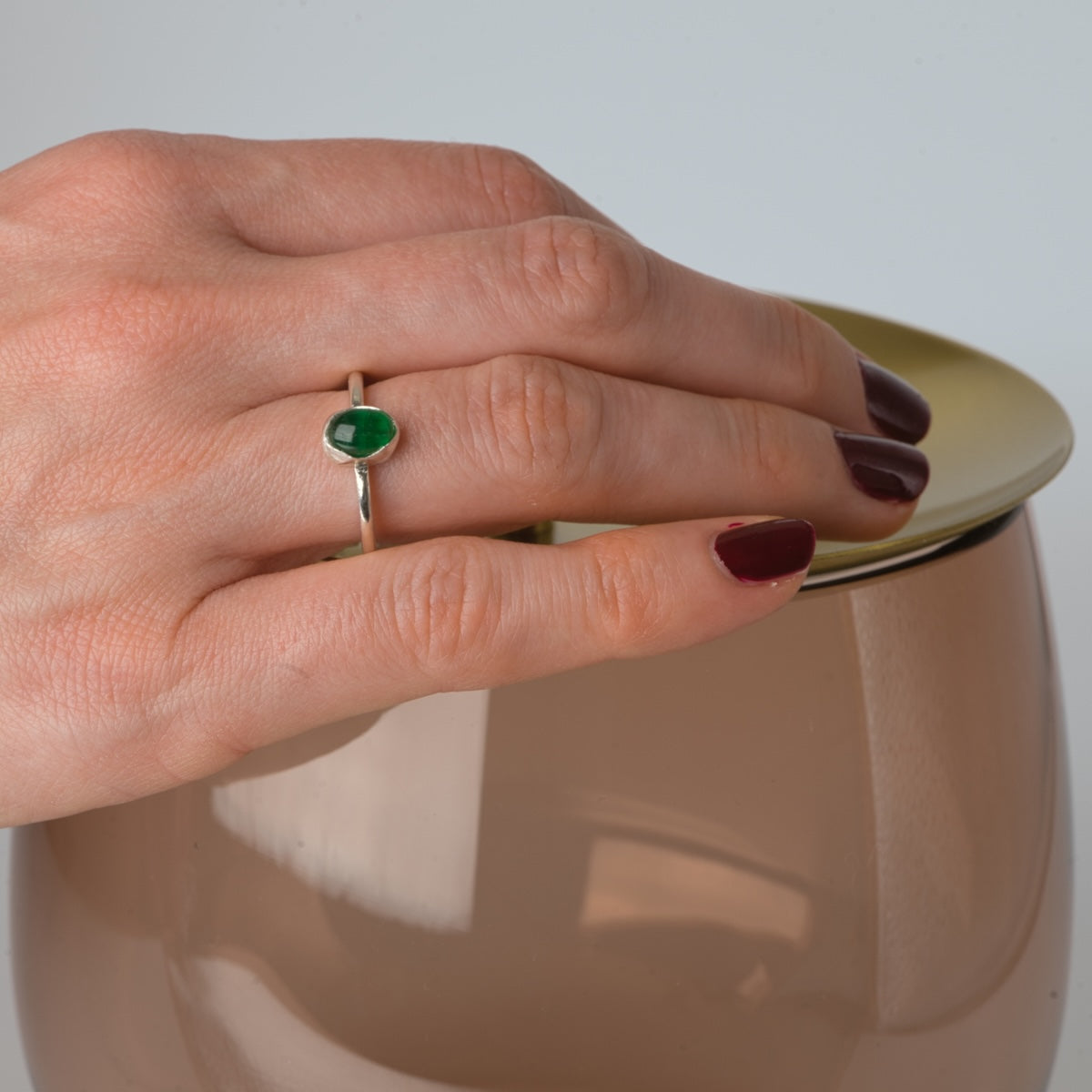 Hand med naturlig smaragd silverring, fotograferad i vinkel för att visa stenens färg och form.