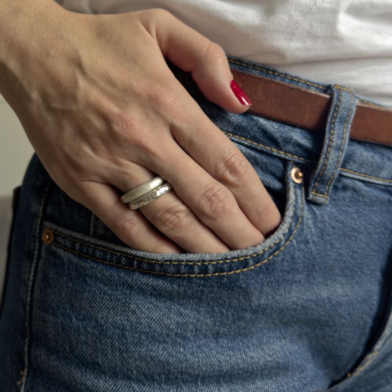 Tjock hamrad och matt silverring från Nude Stockholm på hand i jeansficka.
