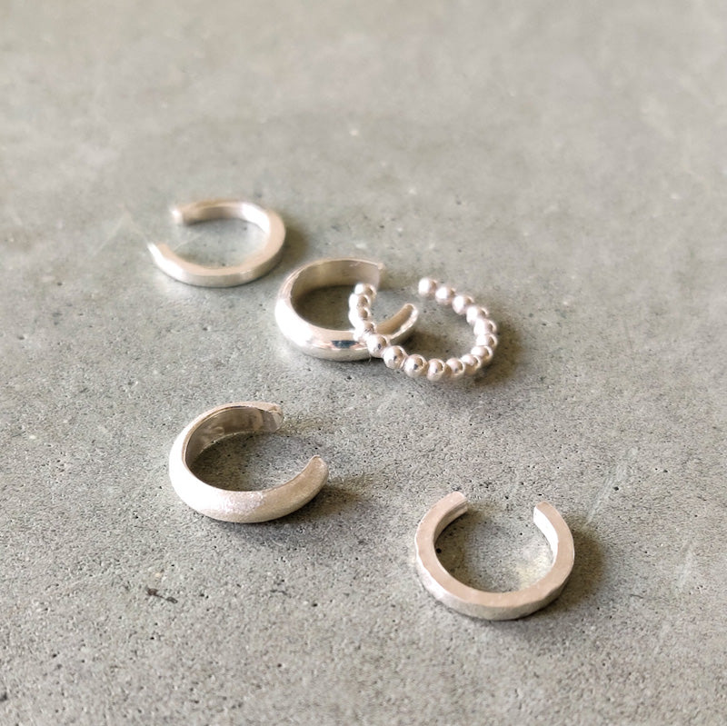 Samling av handgjorda ear cuffs från Nude Stockholm, presenterade sida vid sida på en grå bakgrund.