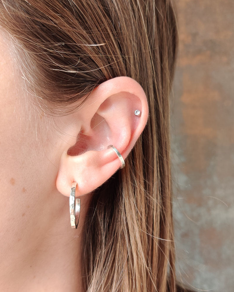 Kantig ear cuff i blank finish som lyser upp ett öra, handgjord i sterlingsilver.