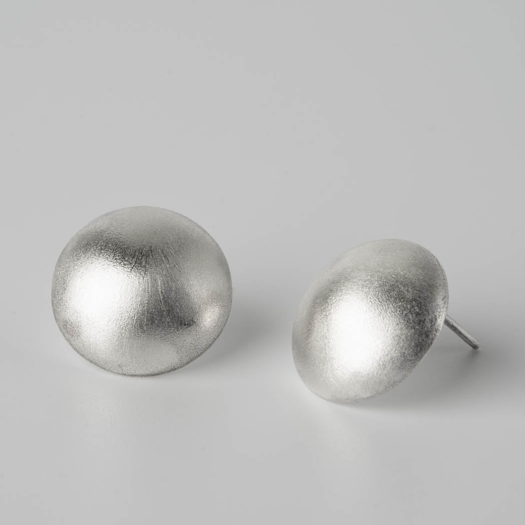 Måneformade handgjorda örhängen i äkta silver med en modern matt design, fotograferade mot vit bakgrund.