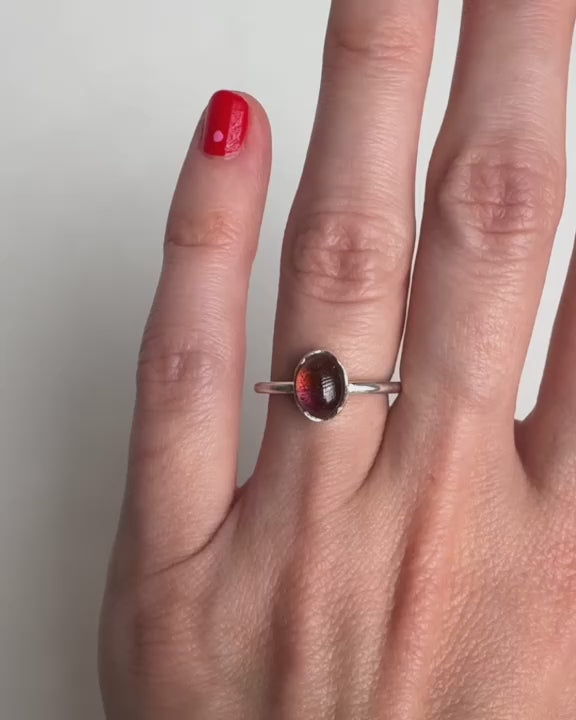 Video som visar en elegant silverring med en rosa turmalin, visad från olika vinklar på en dams hand, vilket framhäver ringens detaljrika design och stenens klara färg.